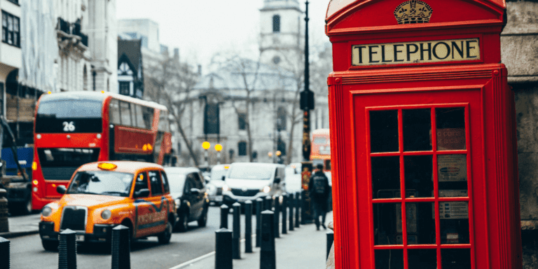 Samochodu jadące Londynem obok budki telefonicznej