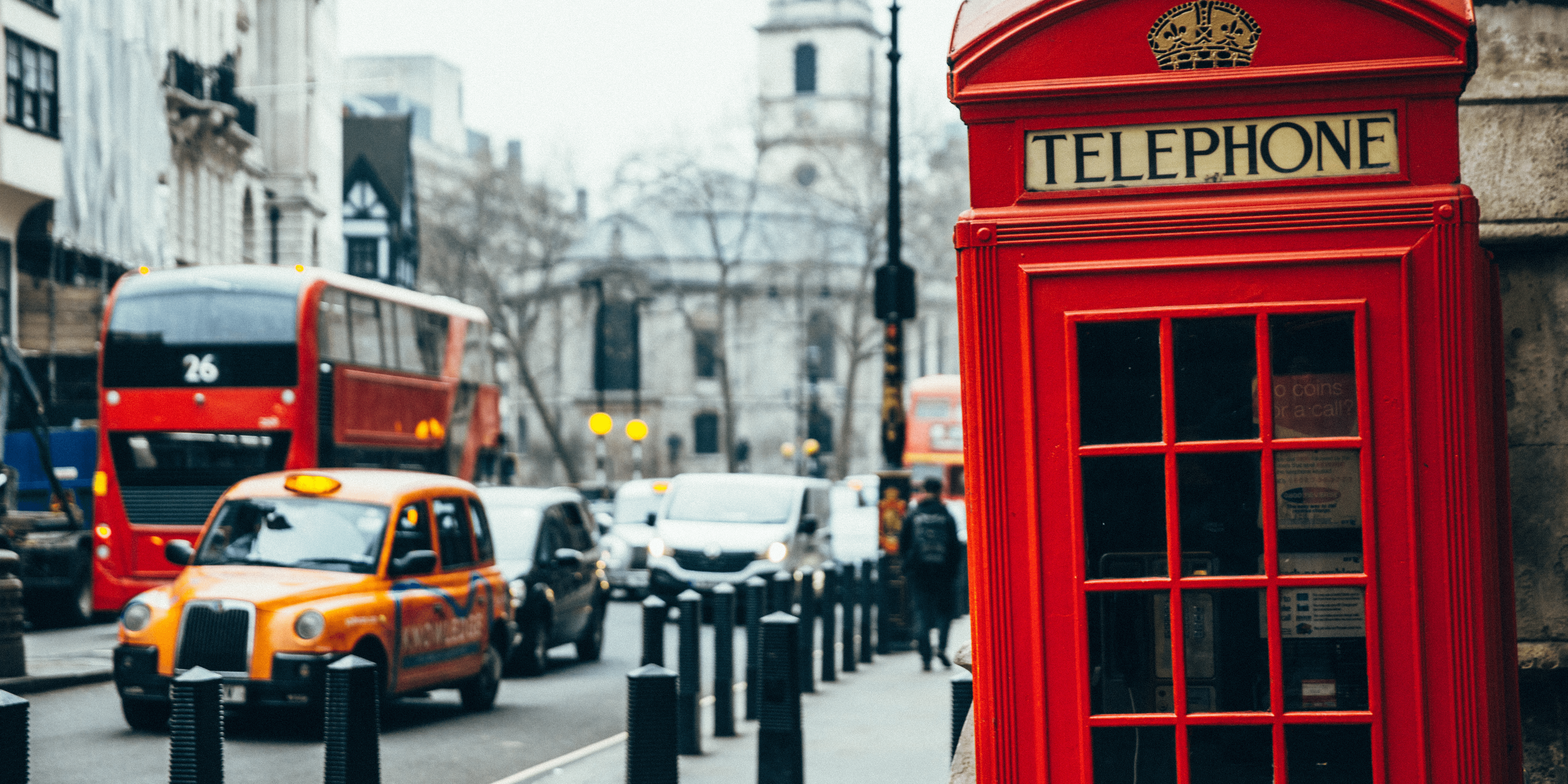 Samochodu jadące Londynem obok budki telefonicznej