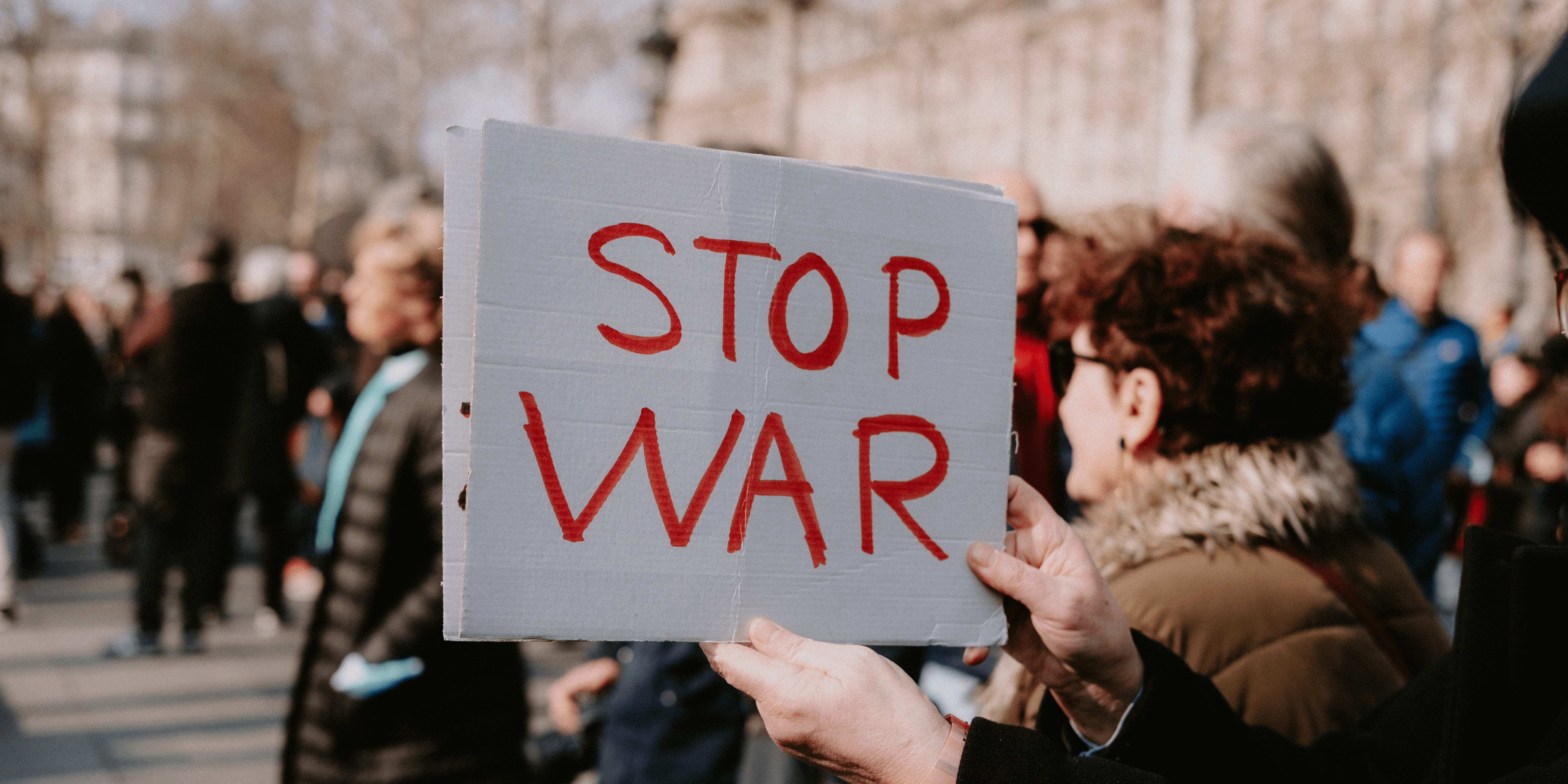 Protestujący z kartką podpisaną "STOP WAR"